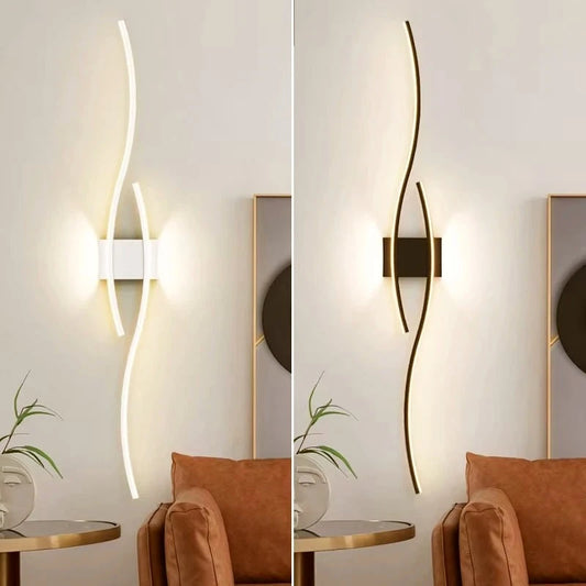 Wave LED wall sconce mounted vertically in white and in black beside a lounge chair