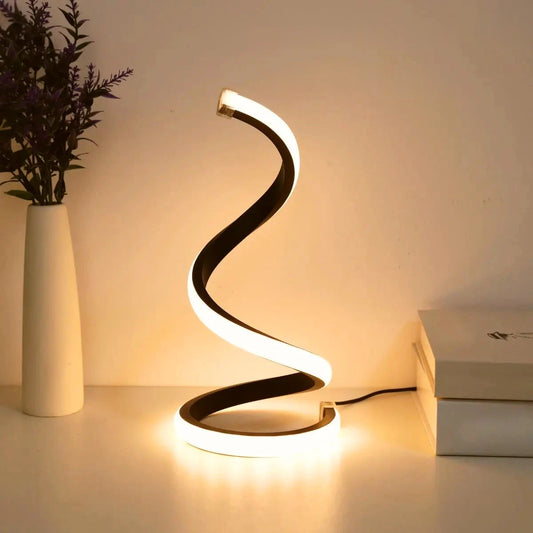 Spiral LED table lamp glowing warm white on a bedside table