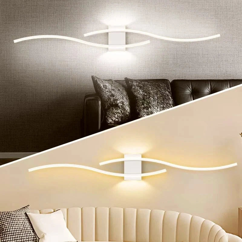 White wave LED wall sconce above a bed casting soft indirect light