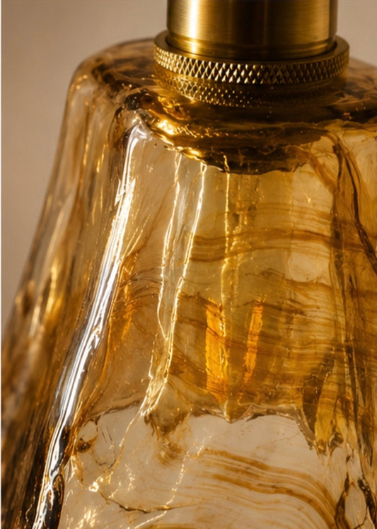 Close-up of hand-formed amber glass shade and knurled brass collar detail on wall sconce
